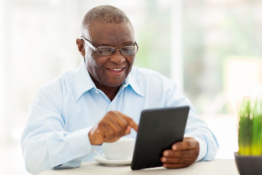 cheerful senior african american man using tablet computer at ho cheerful senior african american man using tablet computer at ho