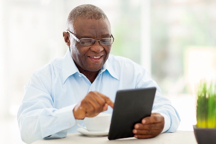 cheerful senior african american man using tablet computer at ho